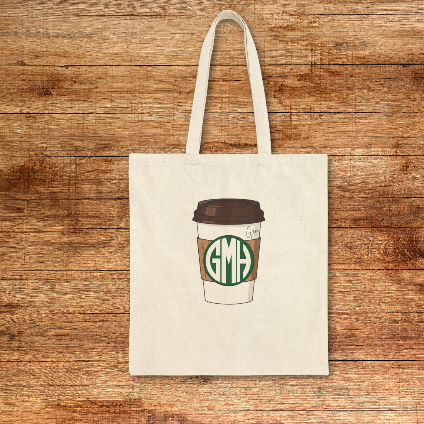 Super simple cotton canvas tote bag with a coffee shop (you know who) style monogram on a to go cup. A name or phrase like "The Charlie" or Pumpkin Spice Latte is also written to the top right. No boxed corners, just a bold monogram on your choice of natural or black canvas bag. 